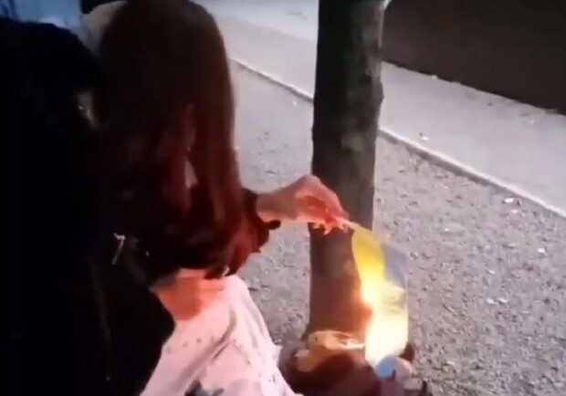 Под смех друзей: в Каменском девушка сожгла украинский флаг - фото: tg huevoe_kamenskoe